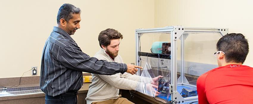 Electrical Engineering Professor pointing at machine students are working on.